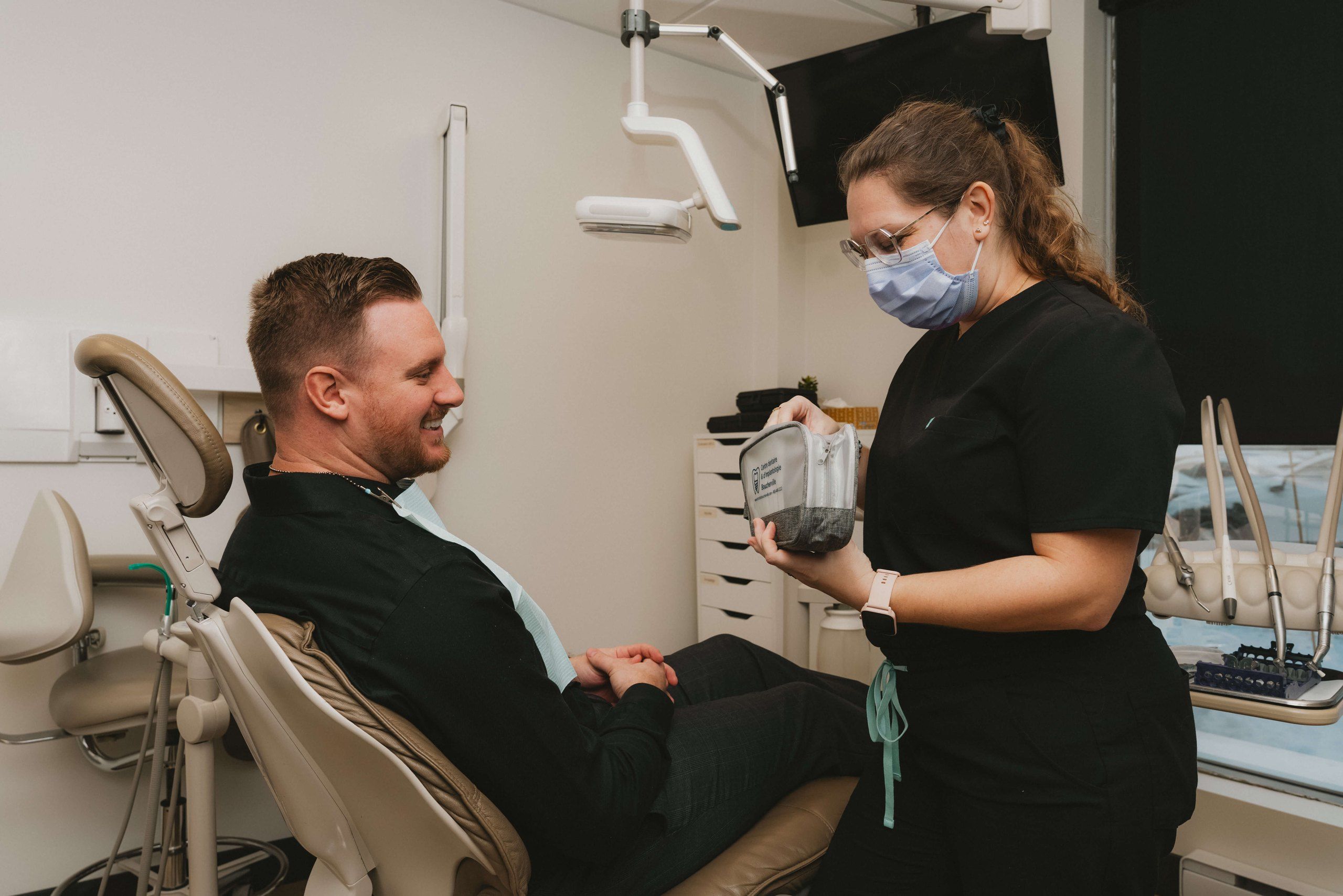 Dentiste souriant avec un patient installé dans le fauteuil dentaire