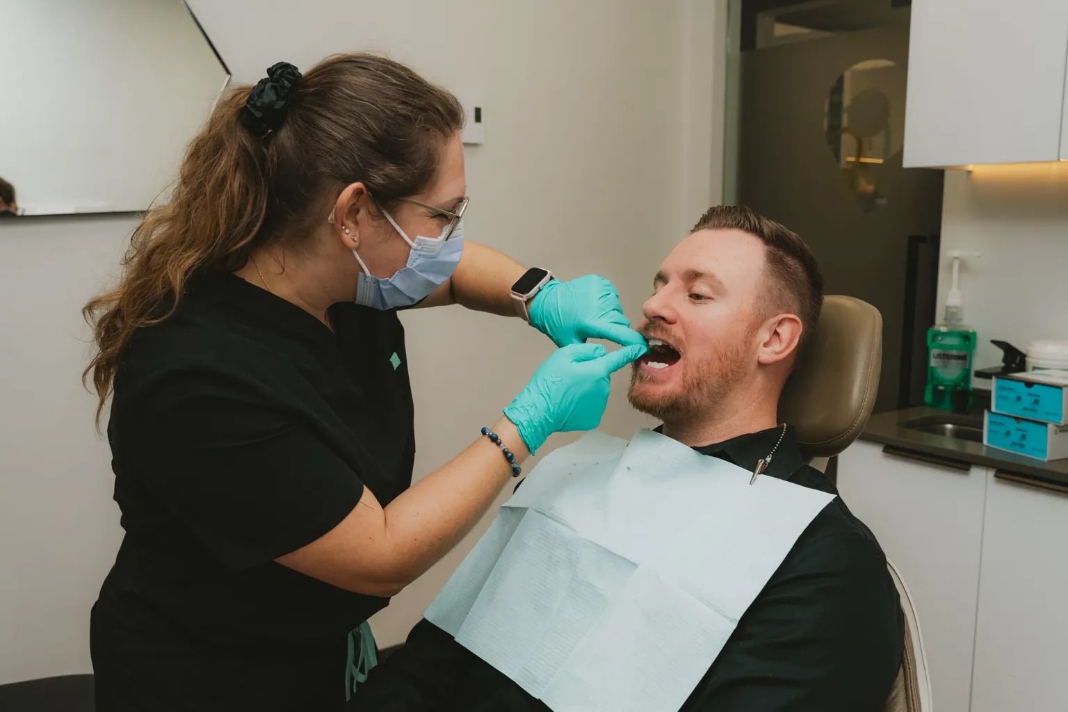 Hygiéniste dentaire effectuant un examen buccal sur un patient lors d’un rendez-vous en clinique dentaire